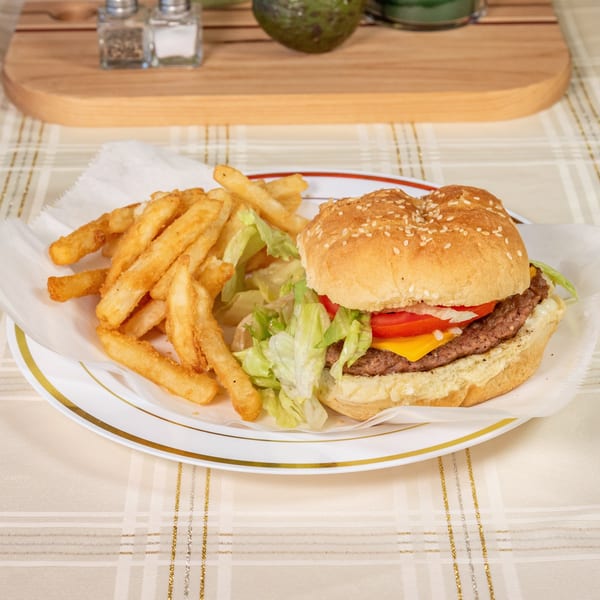 A cheeseburger with lettuce, tomato, onion, and cheese, served with a side of french fries.