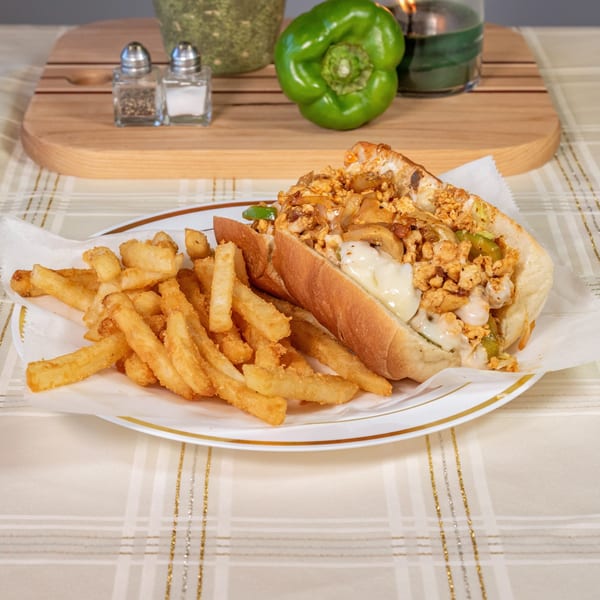 PHILLY STEAK & SUBS cheesesteak with melted cheese, onions, and peppers, served with fries.