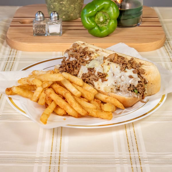 PHILLY STEAK & SUBS cheesesteak with melted cheese and fries on a white plate.